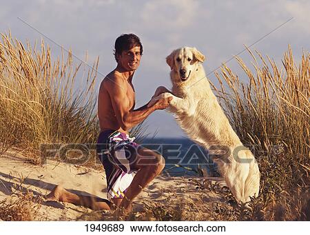 Stock Photo - a man with his golden retriever on los lances beach; tarifa cadiz andalusia spain. Fotosearch
