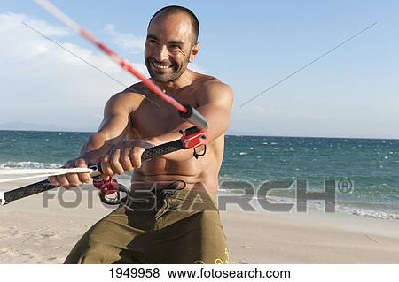 Stock Photo - a man with his windsurfing gear on valdevaqueros beach; tarifa cadiz andalusia spain. Fotosearch
