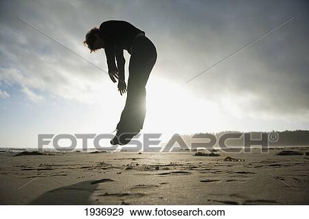 Stock Photo - A Person Jumps In The Air On Hobuck Beach At Sunset; Washington United States Of America. Fotosearch