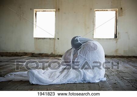Stock Image - A Person Wrapped In A Blanket In An Empty Room; South Caicos Turks And Caicos Islands. Fotosearch