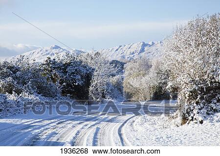Stock Photo - A Snow Covered Road In Winter; Tahilla County Kerry Ireland. Fotosearch
