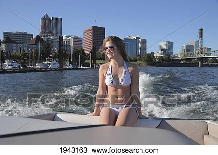 A Teenage Girl In A Bathing Suit Sitting At The Back Of A Boat With The City In The Background; Portland Oregon United States Of America View Large Photo Image Stock Image - A Teenage Girl In A Bathing Suit Sitting At The Back Of A Boat With The City In The Background; Portland Oregon United States Of America. Fotosearch