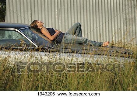 Stock Photograph - A Teenage Girl Laying On The Hood Of A Car; Troutdale Oregon United States Of America. Fotosearch