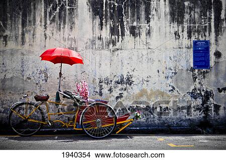 A Traditional Penang Trishaw Sits In Front Of An Old Weathered Wall; Penang Malaysia View Large Photo Image Picture - A Traditional Penang Trishaw Sits In Front Of An Old Weathered Wall; Penang Malaysia. Fotosearch
