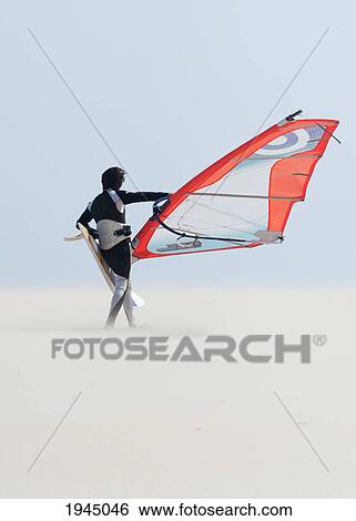 Stock Photograph - a windsurfer walks on the sand of punta paloma beach with his board; tarifa cadiz andalusia spain. Fotosearch