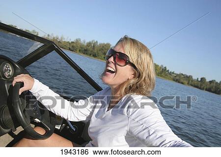 Stock Photograph - A Woman Driving A Ski Boat And Laughing; Portland Oregon United States Of America. Fotosearch
