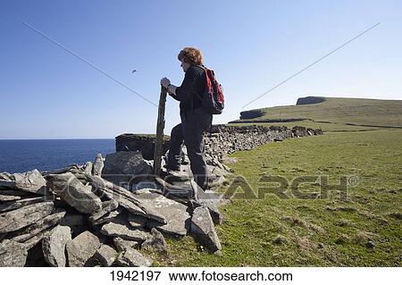 Stock Photo - A Woman Standing Along A Ledge At The Coast; Noss Scotland. Fotosearch