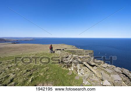 Stock Photography - A Woman Standing Along A Ledge At The Coast; Noss Scotland. Fotosearch