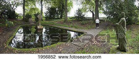 Stock Image - a woman walks around st. mary's well; northumberland england. Fotosearch