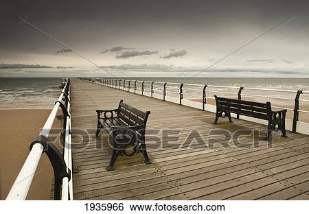 Stock Photograph - A Wooden Pier With Benches Looking Out Over The Beach And Water; Saltburn Cleveland England. Fotosearch