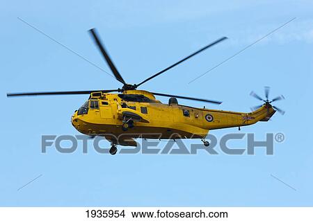 Picture - A Yellow Helicopter Flying In A Blue Sky; Northumberland, England. Fotosearch