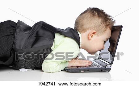 Stock Image - A Young Boy Dressed In A Suit Sees The Reflection Of His Face In The Monitor Of A Laptop Computer; Edmonton Alberta Canada. Fotosearch