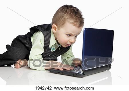 Stock Image - A Young Boy Dressed In A Suit Using A Laptop Computer; Edmonton Alberta Canada. Fotosearch