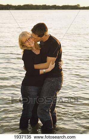 Stock Photography - A Young Couple In An Embrace While Standing In The Lake; Willmar Minnesota United States Of America. Fotosearch