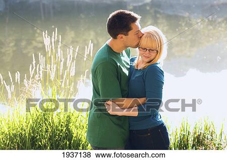 Stock Photo - A Young Couple Kiss In Front Of Sylvan Lake; South Dakota United States Of America. Fotosearch