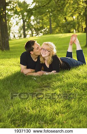 A Young Couple Laying On The Grass In A Park; Willmar Minnesota United States Of America View Large Photo Image Stock Image - A Young Couple Laying On The Grass In A Park; Willmar Minnesota United States Of America. Fotosearch