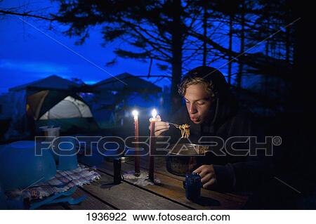 Stock Image - A Young Man Eats From A Pot On A Picnic Table At A Campsite; La Push Washington United States Of America. Fotosearch