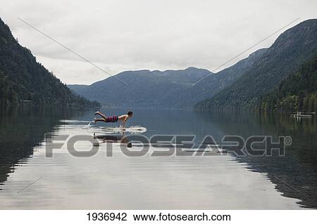 A Young Man Leaps Onto His Body Board In Cameron Lake; British Columbia Canada View Large Photo Image Stock Image - A Young Man Leaps Onto His Body Board In Cameron Lake; British Columbia Canada. Fotosearch