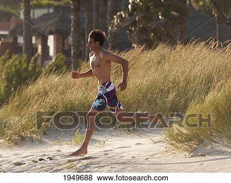 Stock Photo - a young man runs on the beach; tarifa cadiz andalusia spain. Fotosearch