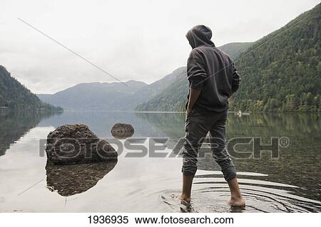 A Young Man Wades In Shallow Water On Cameron Lake; British Columbia Canada View Large Photo Image Stock Photography - A Young Man Wades In Shallow Water On Cameron Lake; British Columbia Canada. Fotosearch