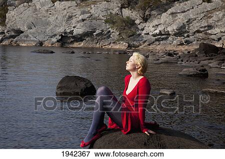 A Young Woman Basks In The Sunshine While Sitting On A Large Rock On Muckross Lake; Killarney County Kerry Ireland View Large Photo Image Stock Photo - A Young Woman Basks In The Sunshine While Sitting On A Large Rock On Muckross Lake; Killarney County Kerry Ireland. Fotosearch