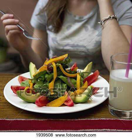 Stock Photo - A Young Woman Eats From A Plate Of Salad; Cusco Peru. Fotosearch