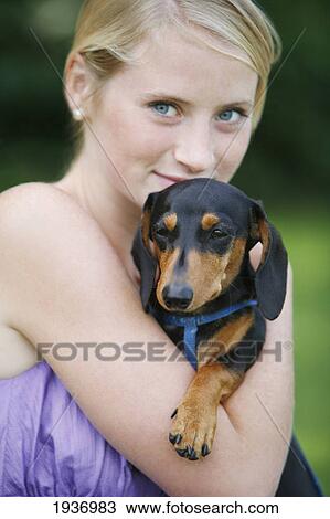 Stock Image - A Young Woman Holds Her Mini Dachshund Dog; Victoria British Columbia Canada. Fotosearch