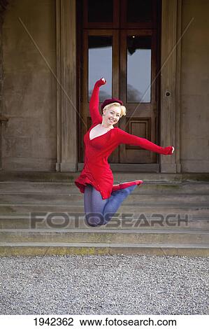 Stock Image - A Young Woman Leaping Into The Air In Front Of Muckross House; Killarney County Kerry Ireland. Fotosearch