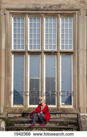 Stock Photo - A Young Woman Sits In Front Of A Large Window Of Muckross House; Killarney County Kerry Ireland. Fotosearch