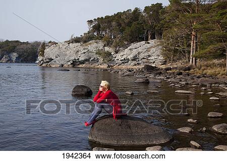 A Young Woman Sits On A Large Rock On Muckross Lake; Killarney County Kerry Ireland View Large Photo Image Picture - A Young Woman Sits On A Large Rock On Muckross Lake; Killarney County Kerry Ireland. Fotosearch