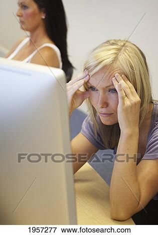 Stock Photo - a young woman struggles to understand as she reads from her computer screen; south shields tyne and wear england. Fotosearch