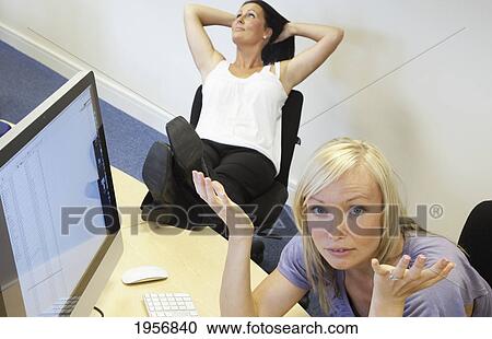 Stock Image - an employee is frustrated while a co-worker neglects work; south shields tyne and wear england. Fotosearch
