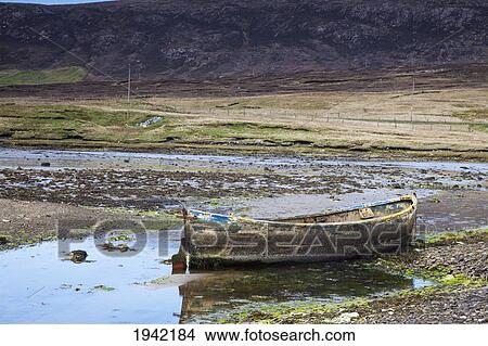Picture - An Old Abandoned Rowboat In Shallow Water; Shetland Scotland. Fotosearch