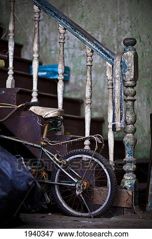 Stock Photo - An Old Staircase With Paint Peeling Provides Support For A Child's Bicycle; George Town Penang Malaysia. Fotosearch