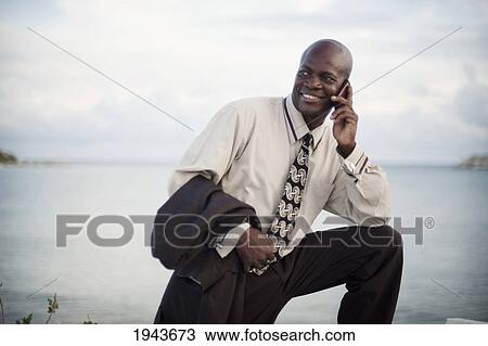 Businessman Using A Cell Phone At The Water's Edge; South Caicos Turks And Caicos Islands View Large Photo Image Stock Image - Businessman Using A Cell Phone At The Water's Edge; South Caicos Turks And Caicos Islands. Fotosearch