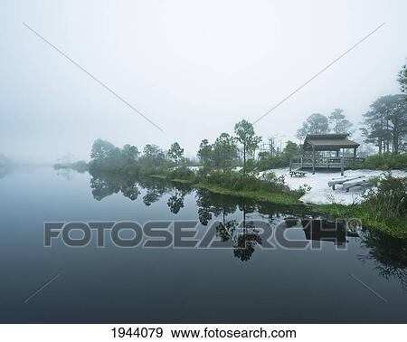 Stock Photo - Canoes And A Small Shelter On The Shore Along The Water; Pensacola Florida United States Of America. Fotosearch