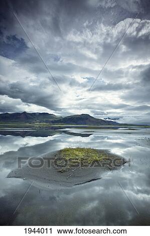 Stock Image - Clouds Reflected In The Tranquil Water Along The Coastline; Iceland. Fotosearch