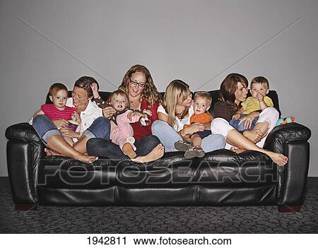 Stock Image - Four Mothers And Their Children On A Couch; Edmonton Alberta Canada. Fotosearch
