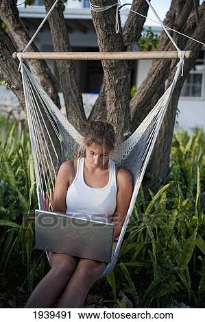 Stock Image - Girl Working On A Laptop While Sitting In A Hammock; South Caicos Turks And Caicos Islands. Fotosearch