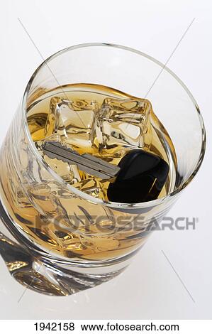 Stock Photo - High Angle View Of A Partially Filled Whiskey Glass With Ice And A Car Key In The Glass. Fotosearch