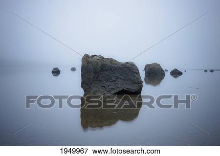 Stock Photo - large boulders reflected in the water; iceland. Fotosearch