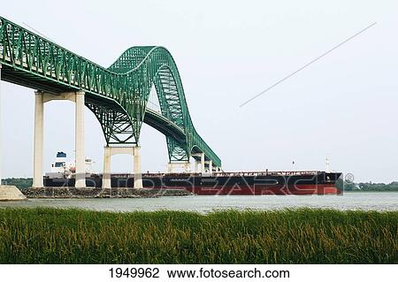 Stock Image - laviolette bridge with a large ship passing beneath; trois-rivieres quebec canada. Fotosearch