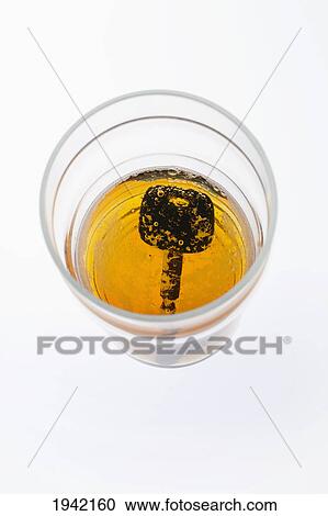 Stock Image - Looking Down Into A Partially Filled Beer Glass With A Car Key In The Bottom Of The Glass. Fotosearch