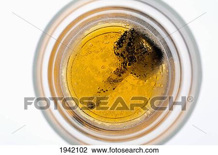 Stock Image - Looking Down Into A Partially Full Beer Glass With A Car Key On The Bottom Of The Glass. Fotosearch