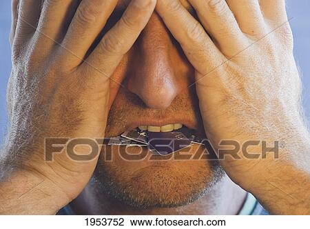 Stock Image - man covering his face with his hands and with cut up pieces of credit card in his mouth; torremolinos malaga andalusia spain. Fotosearch