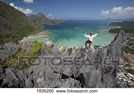 Man Enjoys View From Limestone Spires Over Coastal Village; El Nido, Palawan, Philippines View Large Photo Image Stock Image - Man Enjoys View From Limestone Spires Over Coastal Village; El Nido, Palawan, Philippines. Fotosearch