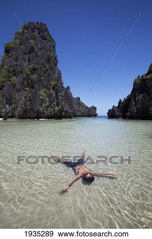 Man Floating In Clear Water Of Small Lagoon; Miniloc Island, Palawan, Philippines View Large Photo Image Stock Photo - Man Floating In Clear Water Of Small Lagoon; Miniloc Island, Palawan, Philippines. Fotosearch