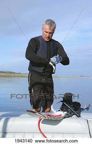 Stock Image - Man Putting On Water Skiing Gloves On The Back Of A Boat; Troutdale Oregon United States Of America. Fotosearch