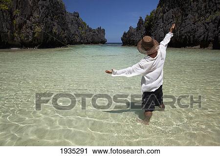 Man Standing In Clear Water Of Small Lagoon; Miniloc Island, Palawan, Philippines View Large Photo Image Stock Image - Man Standing In Clear Water Of Small Lagoon; Miniloc Island, Palawan, Philippines. Fotosearch