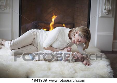 Mother And Baby On Carpet In Front Of Fireplace; Jordan Ontario Canada View Large Photo Image Stock Photo - Mother And Baby On Carpet In Front Of Fireplace; Jordan Ontario Canada. Fotosearch